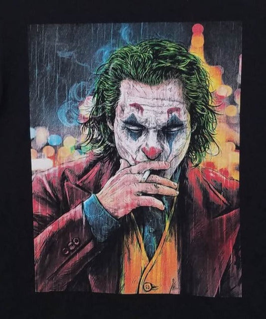 "2019 Joker Smoking T-Shirt featuring a colorful graphic of the Joker in makeup and suit, smoking against a city lights backdrop. Black unisex tee, available in sizes Small to 3XL."