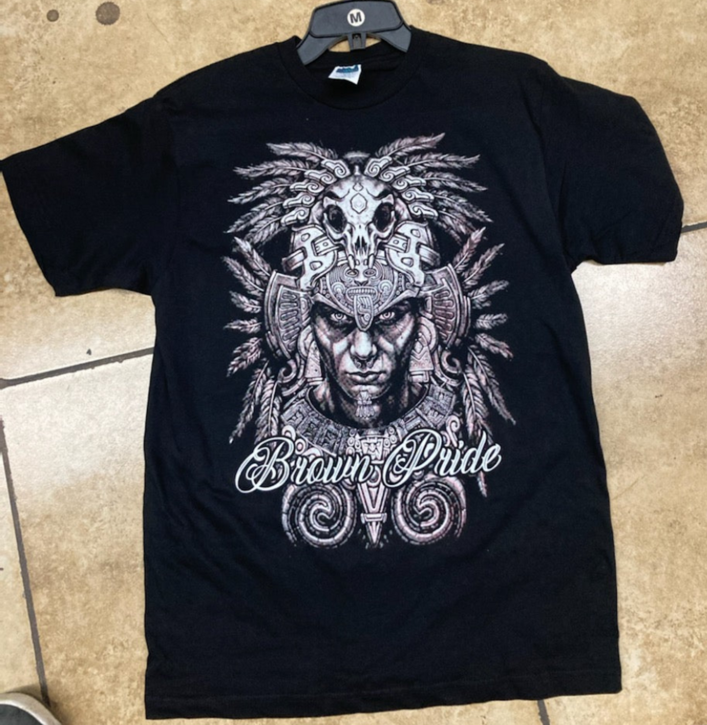 "Brown Pride" Adult Unisex Silkscreen T-Shirt featuring an intricate Aztec warrior design on a black background. Available in sizes Small-2XL.