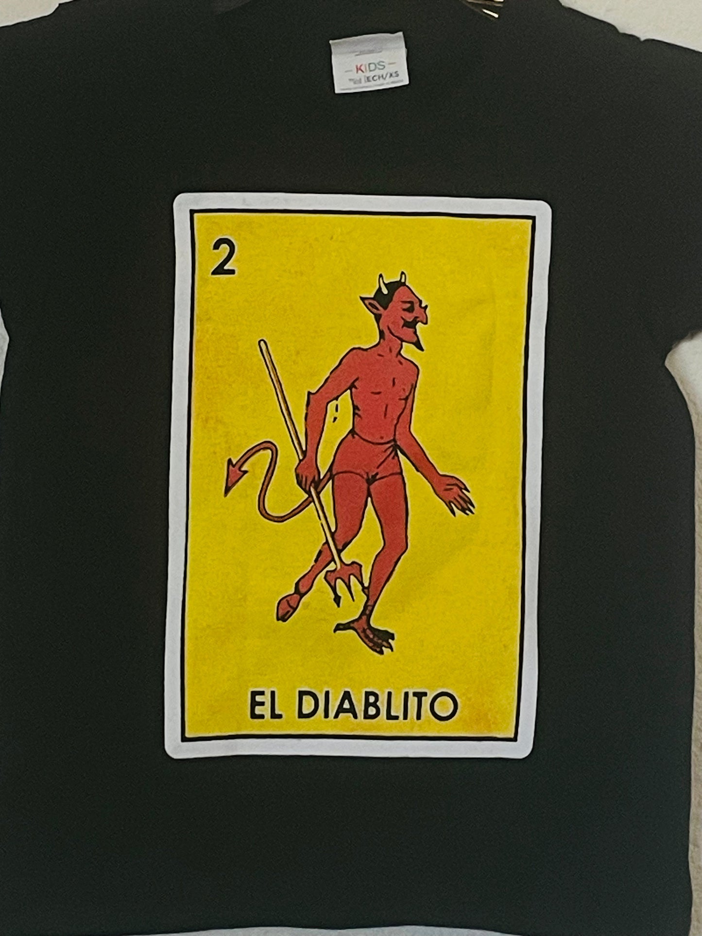 The "El Diablito (Skinny)" Boys Youth Silkscreen Novelty T-Shirt features a bold, playful graphic of El Diablito. Available in sizes XS-XL youth from JB Accessories05