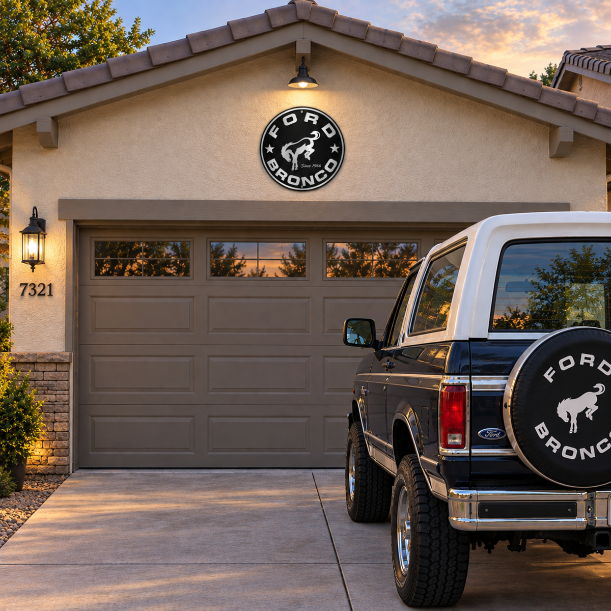 Ford Bronco round metal sign displayed inside a Bronco garage beside a Ford Bronco, tool chest, and garage storage cabinets.