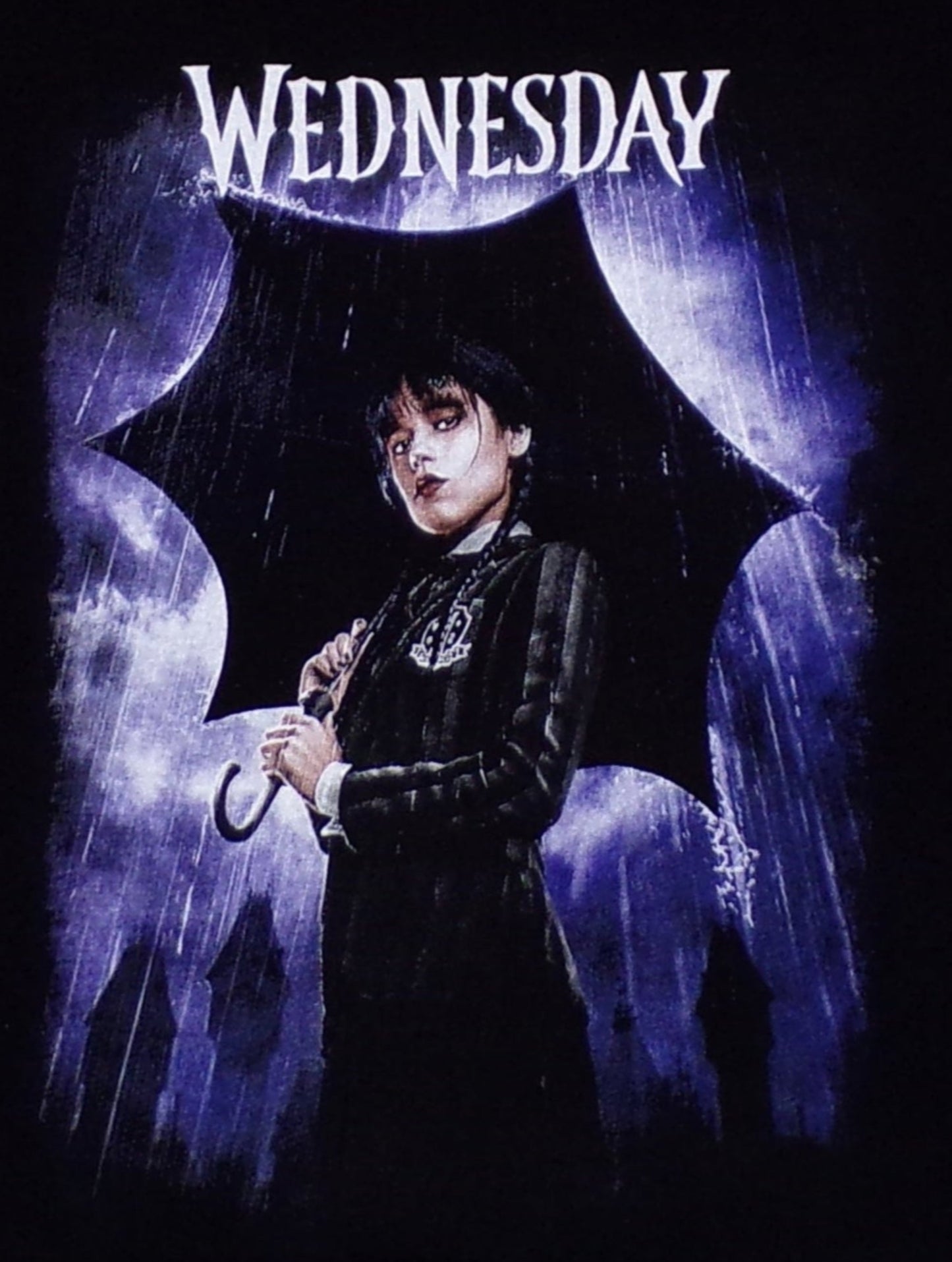 Youth T-shirt featuring Wednesday Addams standing in the rain, showcasing her gothic style and iconic look from The Addams Family. Available in XS-XL