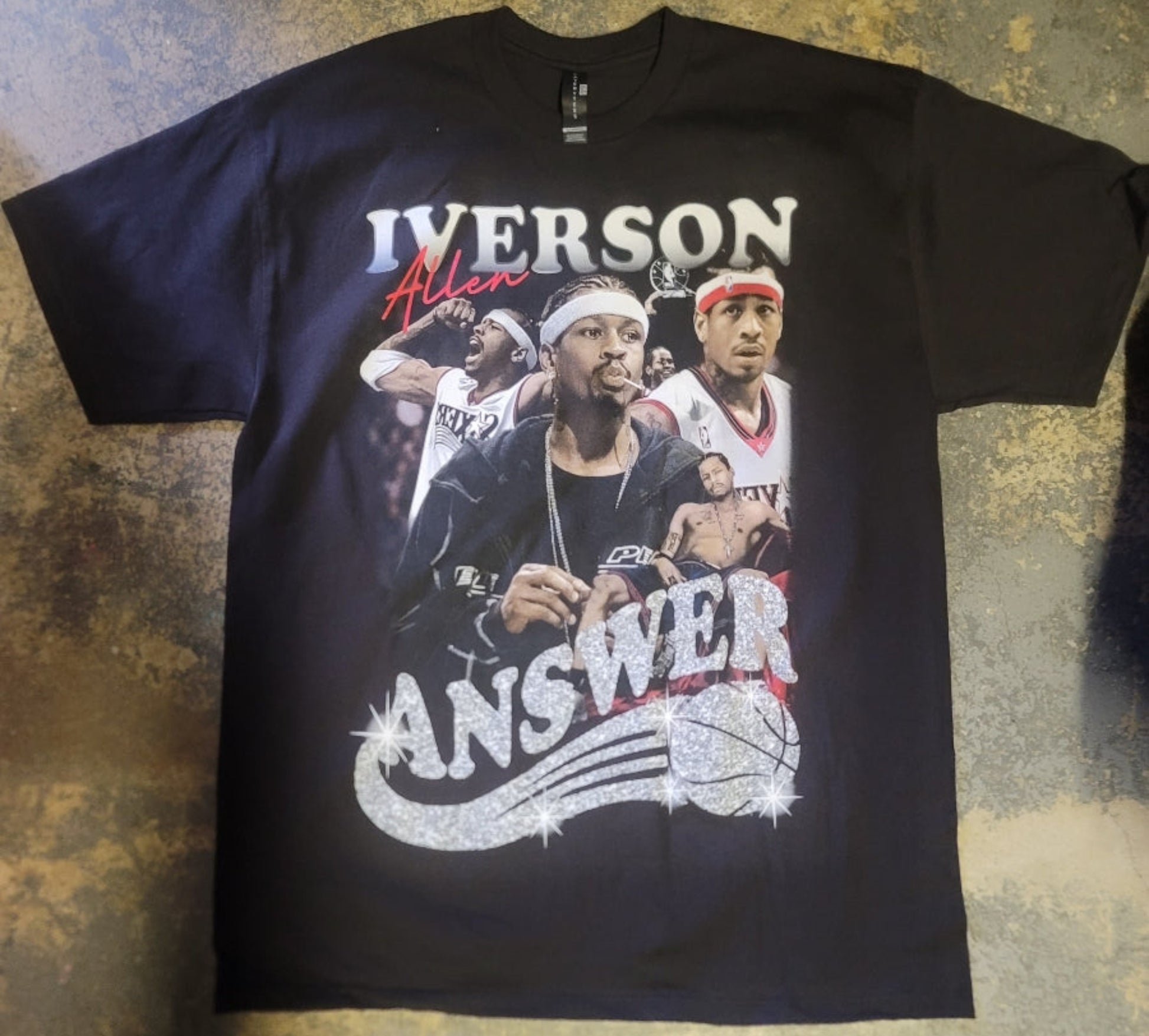 Black “Allen Iverson – The Answer” T-shirt featuring a collage of Iverson with a glitter-style logo and bold basketball tribute design.