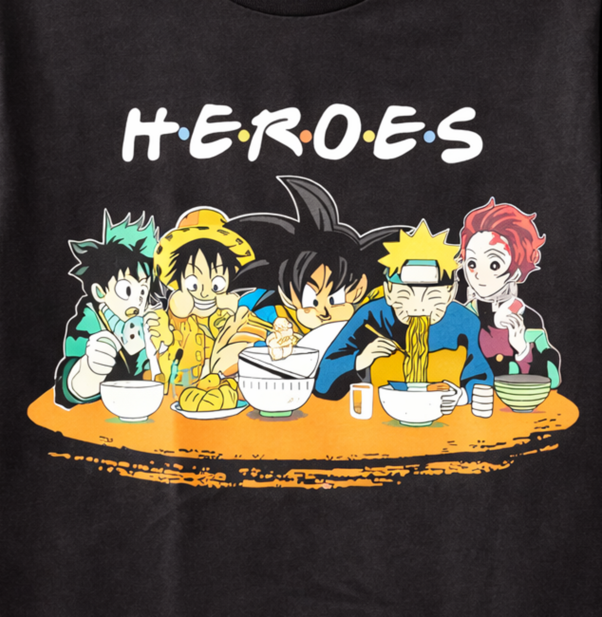Close-up of the Anime Heroes crossover T-shirt showing Deku, Luffy, Goku, Naruto and Tanjiro sharing a meal beneath the HEROES design.