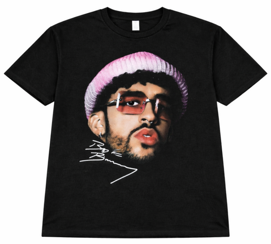 Front view of Bad Bunny Pink Beanie Portrait T-shirt featuring artist in pink knit hat and tinted glasses with signature printed in authentic silkscreen detail.
