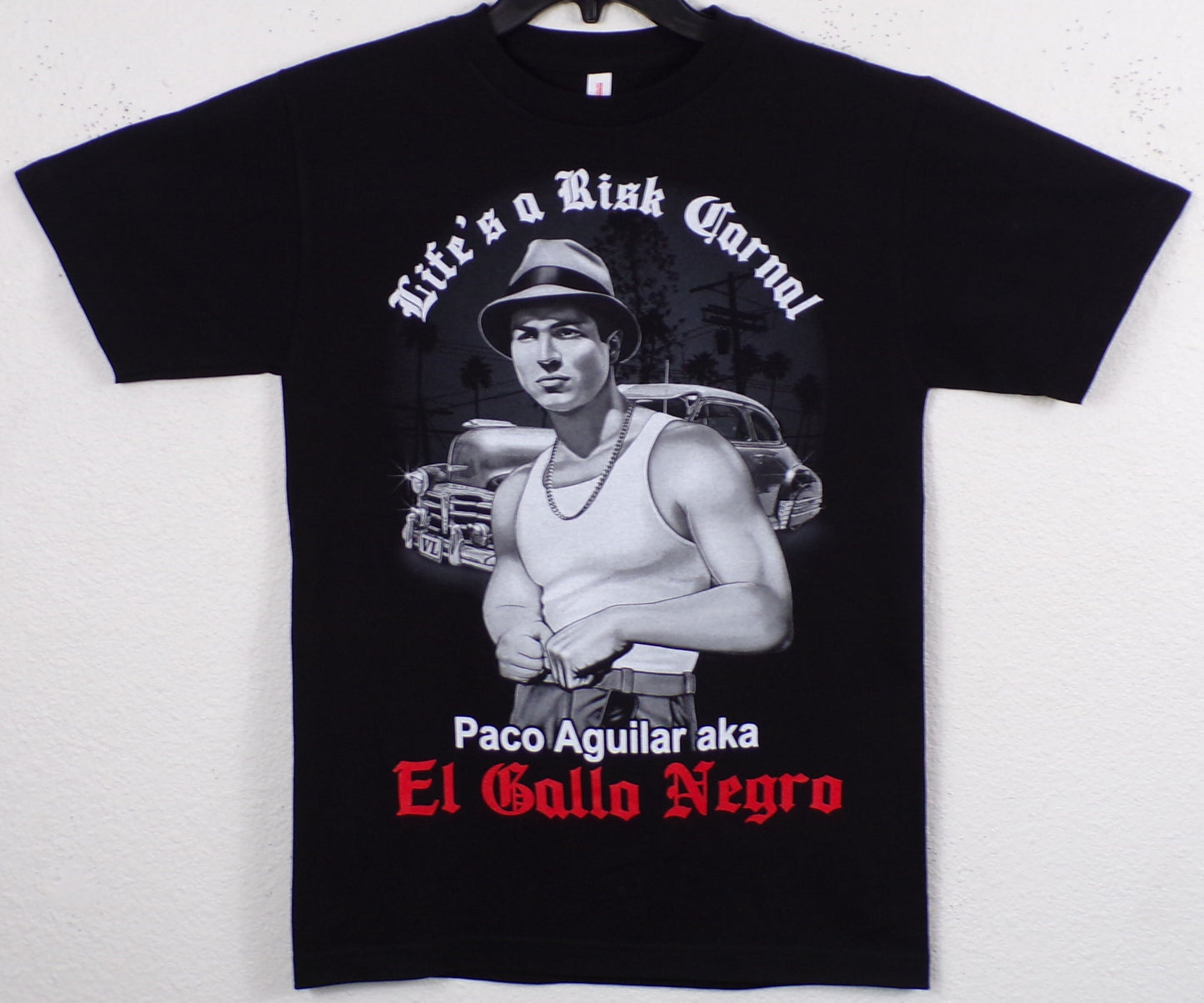 “Blood In Blood Out – Life’s A Risk Carnal” T-shirt featuring Paco Aguilar (El Gallo Negro) in grayscale silkscreen print.