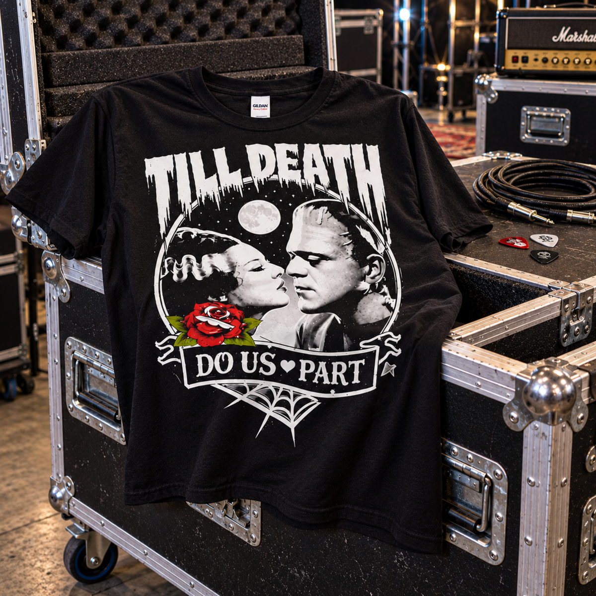 Till Death Do Us Part black T-shirt displayed on backstage road cases with an amp and audio gear, featuring Bride of Frankenstein and Frankenstein’s monster.