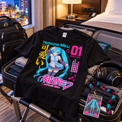 Hatsune Miku 01 black T-shirt laid across an open suitcase in a hotel room, featuring Miku, Japanese lettering and bright neon Vocaloid artwork.