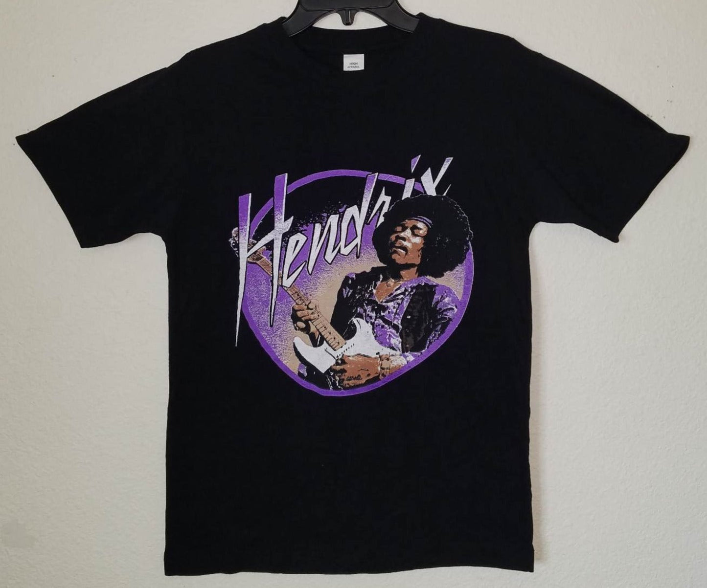 Black “Jimi Hendrix – Purple Haze” unisex T-shirt featuring Hendrix playing guitar with a vivid purple background design, Small–3XL.
