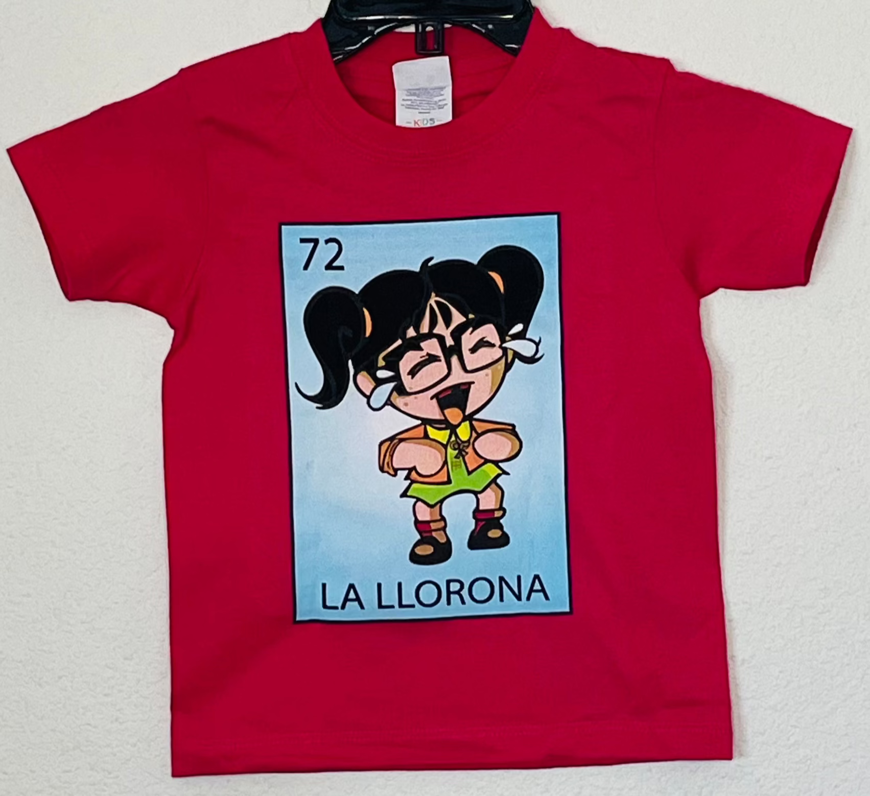 La Llorona Lotería Style Youth T-Shirt featuring a weeping girl design, inspired by Mexican folklore. Available in sizes XS-XL.