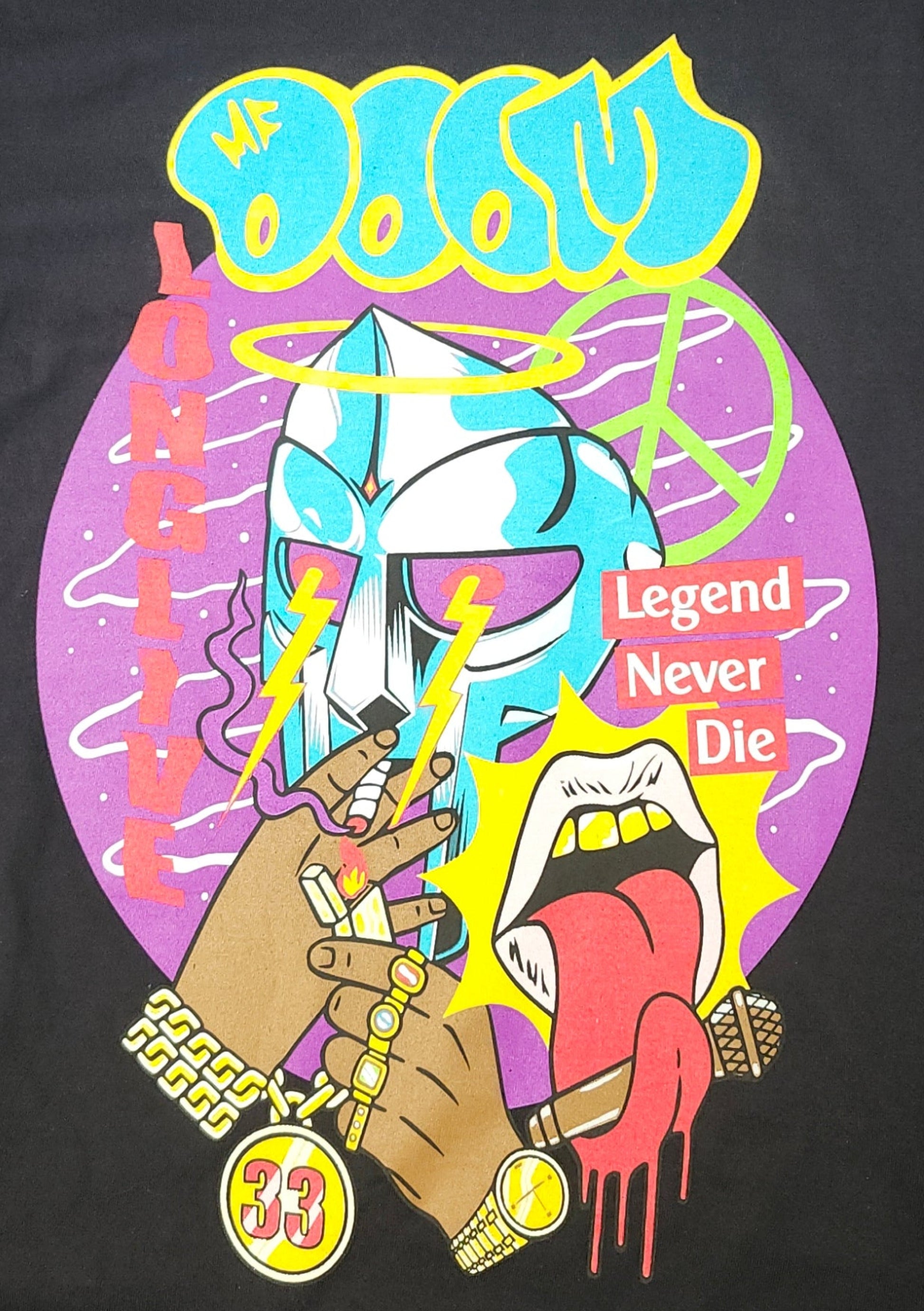 Black “MF DOOM – Legend Never Die” T-shirt featuring cartoon mask design, gold jewelry, and graffiti tribute text.