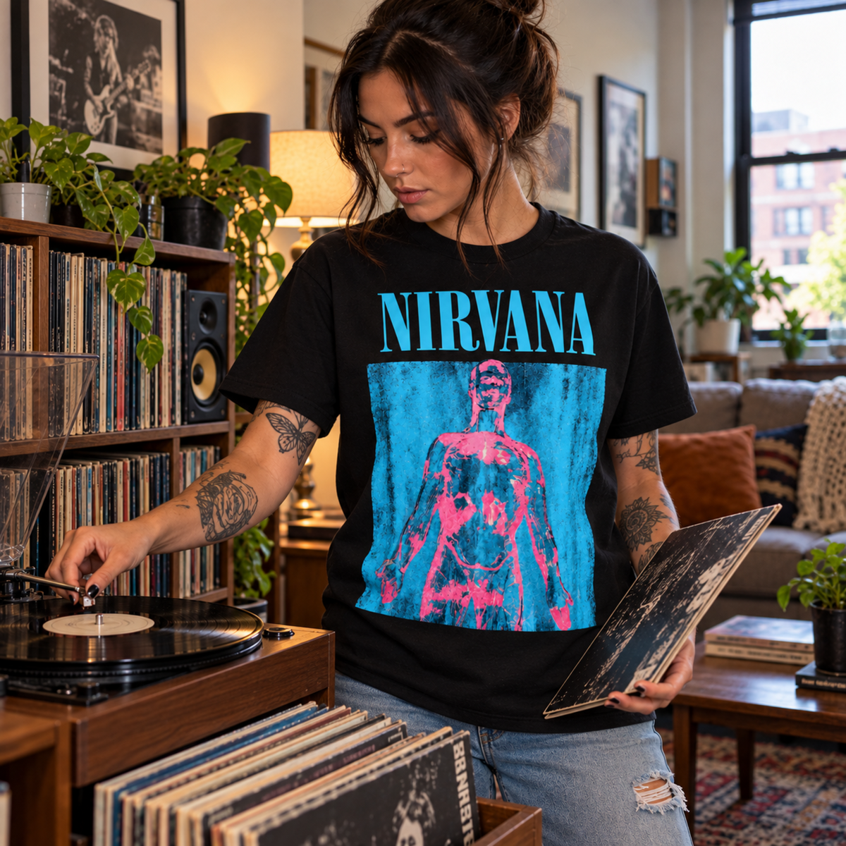 Nirvana Sliver black T-shirt displayed on a record store counter surrounded by vinyl, featuring the bold blue and pink graphic—a strong pick for grunge fans.