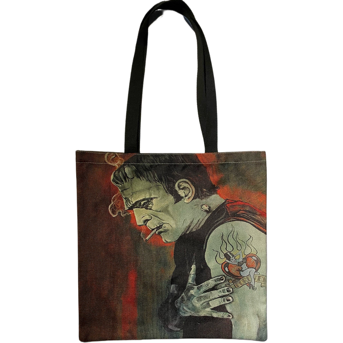 Cream Rockabilly Frankenstein Heartbroken double-sided canvas tote bag with black handles, featuring Frankenstein's Monster smoking a cigarette, wearing a sleeveless black shirt, and displaying a colorful heart tattoo against a distressed red background.