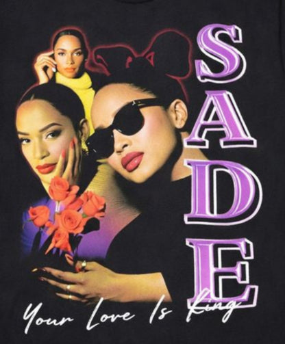 Black “Sade – Your Love Is King” unisex T-shirt featuring a multi-image collage of Sade with purple and red tones, Small–3XL.