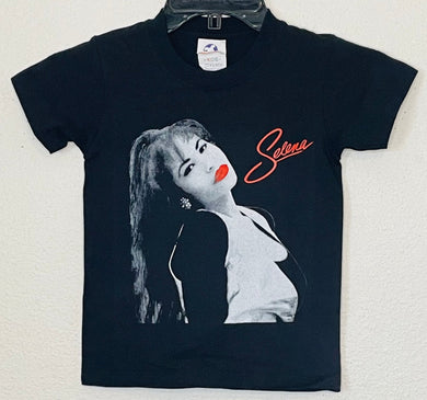 Celebrate the unforgettable Selena with the ‘Selena Red Lips’ Youth Silkscreen T-Shirt! Featuring her bold red lips and iconic style, this tee captures her inspiring legacy and superstar energy. Available in XS-XL
