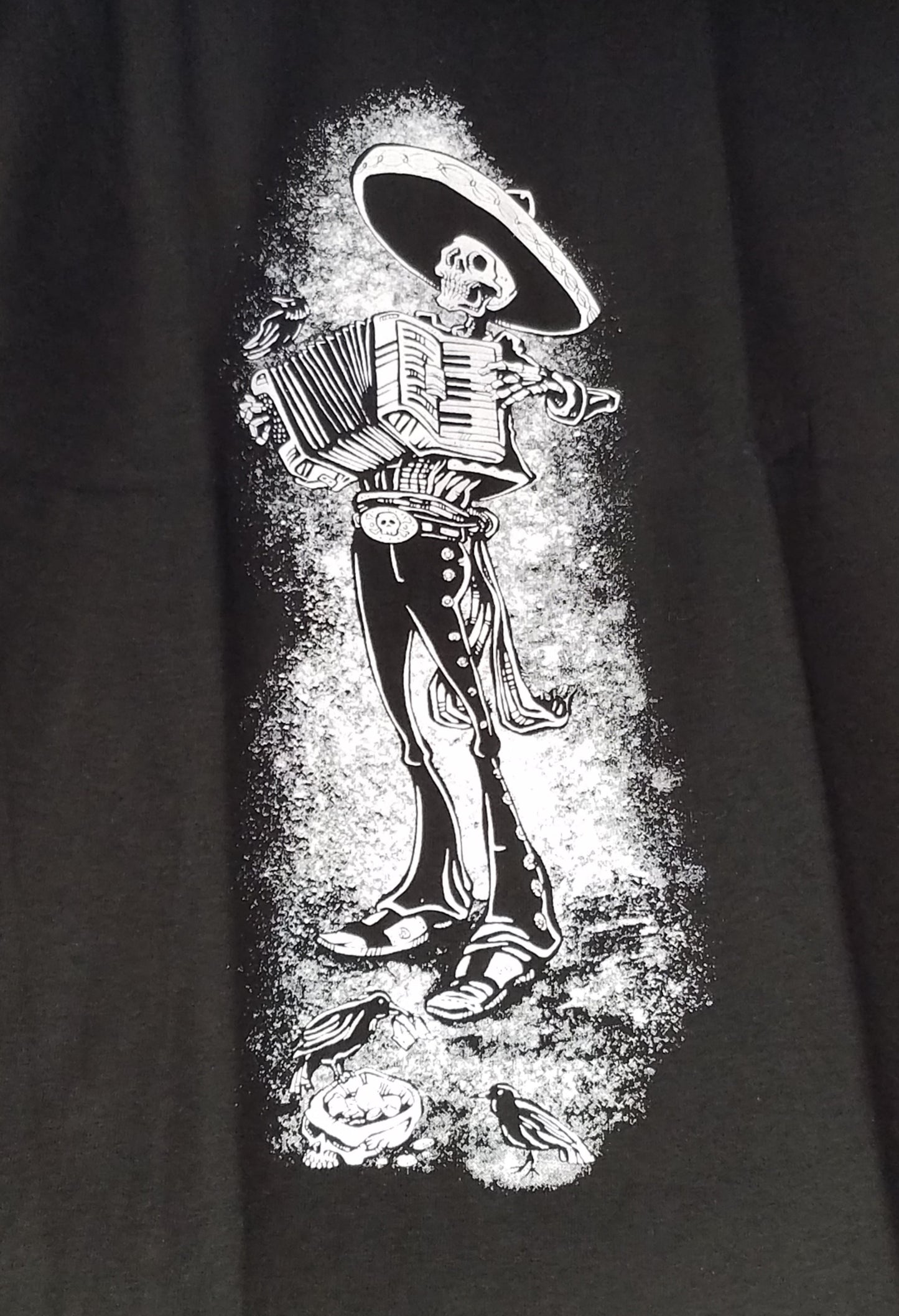 Skeleton Mariachi Accordion Player T-Shirt – A detailed graphic of a skeleton dressed in traditional mariachi attire, passionately playing an accordion. Bold and eye-catching design on a high-quality cotton tee. Available in sizes Small-2XL.