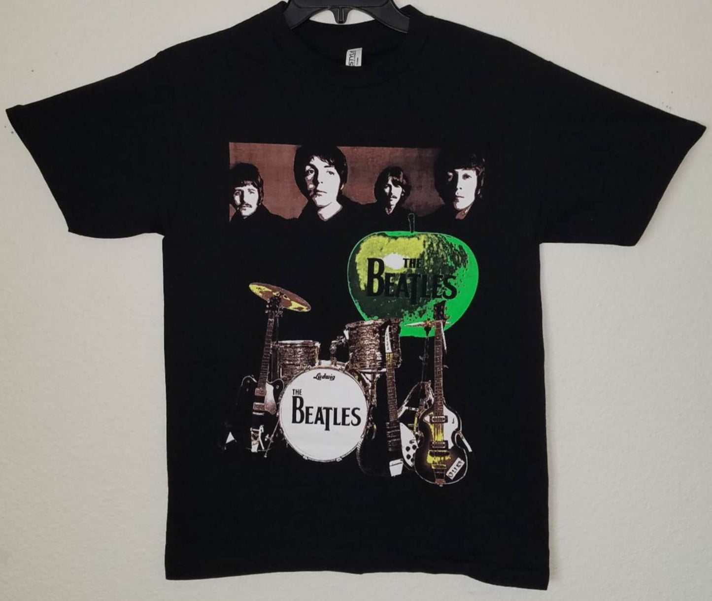 Front view of The Beatles green apple graphic T-shirt featuring band portrait and instruments printed in silkscreen on black cotton tee