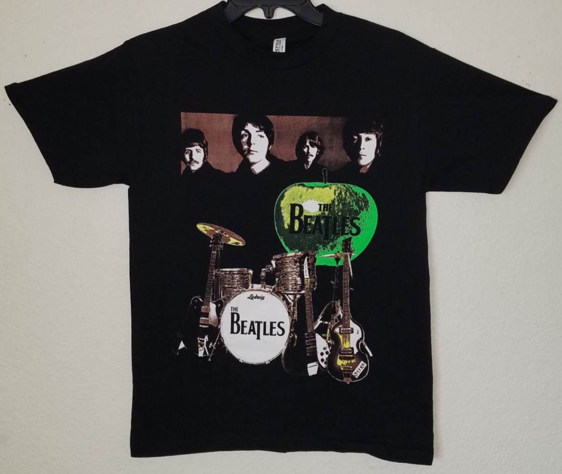 Front view of The Beatles green apple graphic T-shirt featuring band portrait and instruments printed in silkscreen on black cotton tee