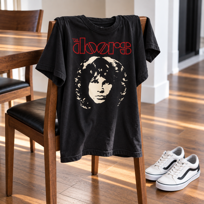 The Doors Jim Morrison Face black T-shirt displayed over a dining chair with sneakers nearby, featuring the Morrison portrait and red logo—a standout piece for fans.