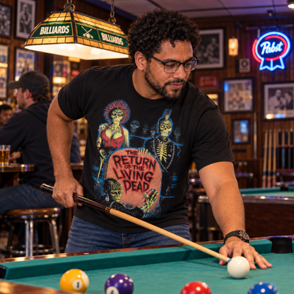 Man wearing The Return of the Living Dead 1985 black graphic T-shirt while shooting pool in a billiards hall, featuring the colorful zombie tombstone design.